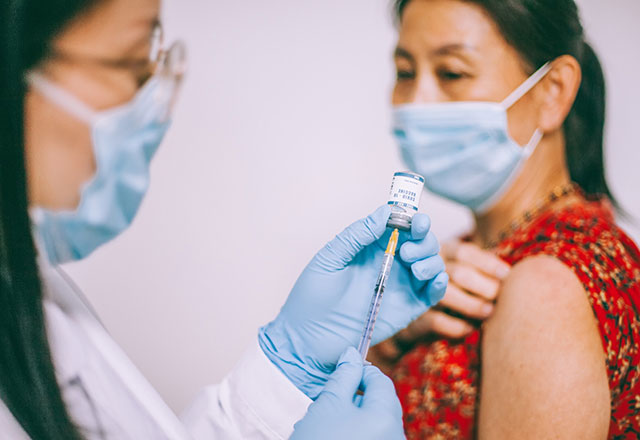 a health care provider preps a vaccine for a patient