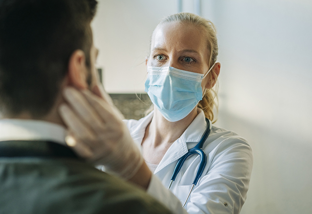 A masked provider examines a patient.
